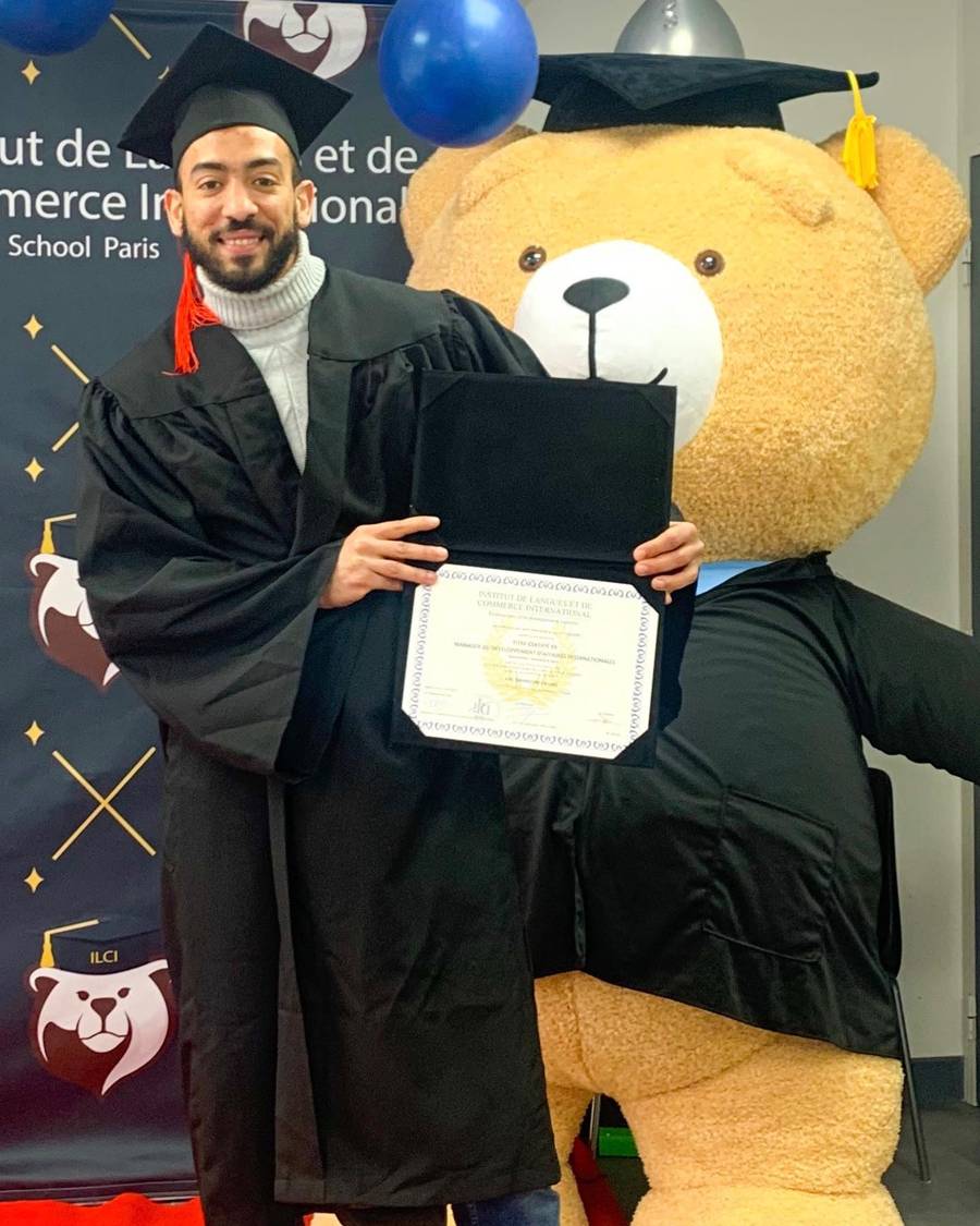 Chouaib Rahmouni en tenue de remise de diplôme, diplôme en main